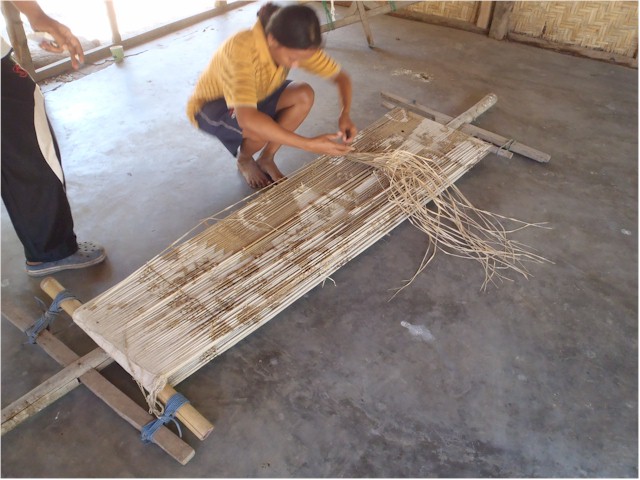 The warp threads are prepared on this frame and the sections to be left un-dyed are tied with straw...