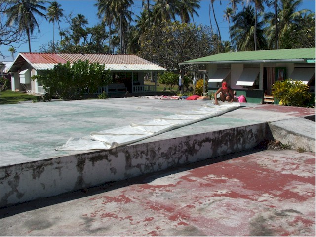 Folding up our torn mainsail on an abandoned water tank ashore.
